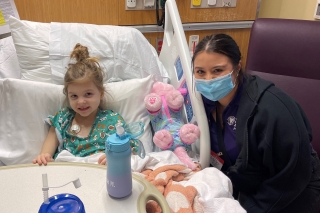 A young girl in a hospital bed being visited by a woman