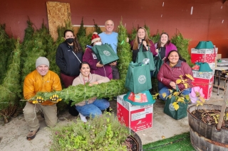 A group of volunteers preparing bundled Christmas trees and donation packages