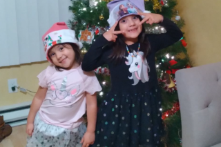 Two smiling young girls with their decorated Christmas tree
