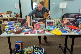 A person setting up a display table of various board games and toys