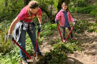 A parent and child helping to trim plants in Forest Park