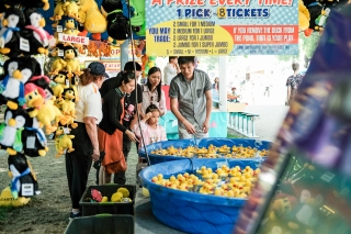 A family at the Portland Rose Festival playing a game with rubber ducks floating in a plastic swimming pool