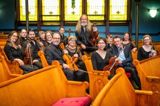 Members of the Portland Baroque Orchestra sitting in pews of a church