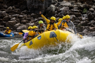 A group of rafters in a raft going through a rapid