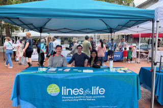 Three people representing Lines for Life sitting at a display booth for the organization