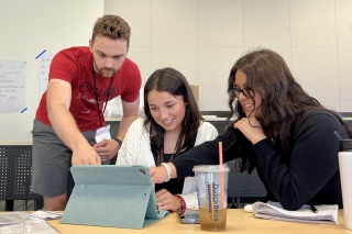 Volunteers pointing at the laptop screen with a business student