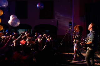 A band playing on stage with crowd cheering during Albert Abbey Foundation's New Year's Eve party