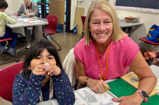 A volunteer with a child working on writing in a workbook