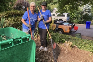 Two H.O.P.E volunteers raking yard debris