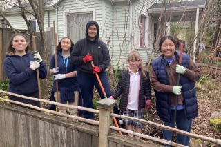 Five young H.O.P.E volunteers with gardening tools working in a front yard